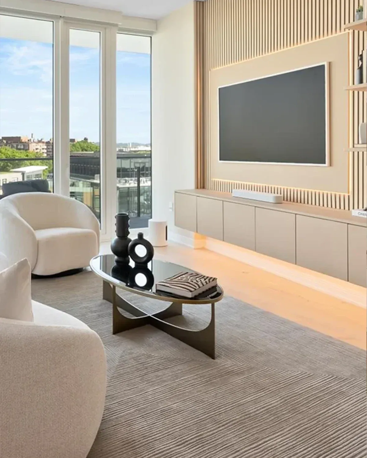 Living room with a slatted oak media wall, white armchairs and a round coffee table