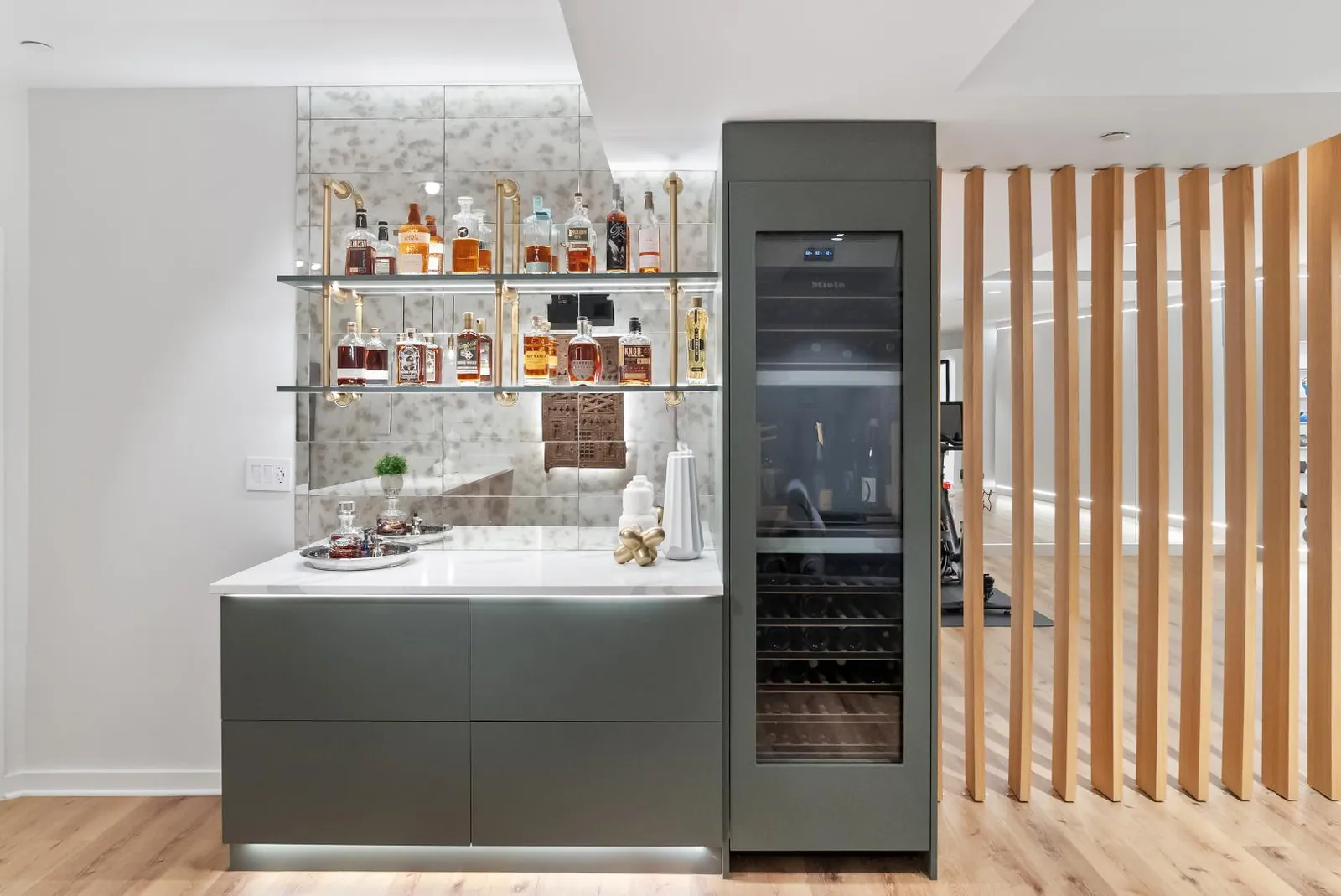 Home bar with mirrored shelving, wine fridge and a vertical oak slat divider