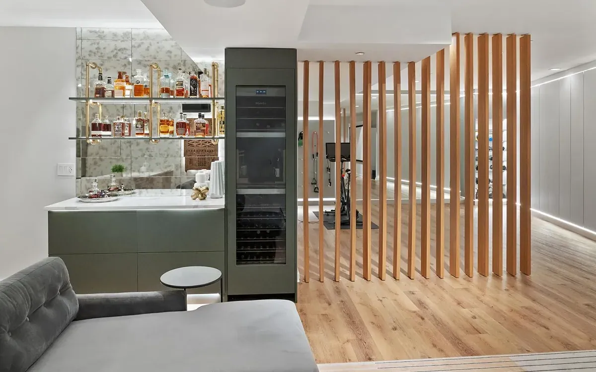 Home bar with mirrored shelving, wine fridge and a vertical oak slat divider